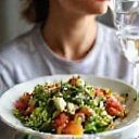 A person drinking water and eating salad, symbolizing hydration and portion control.